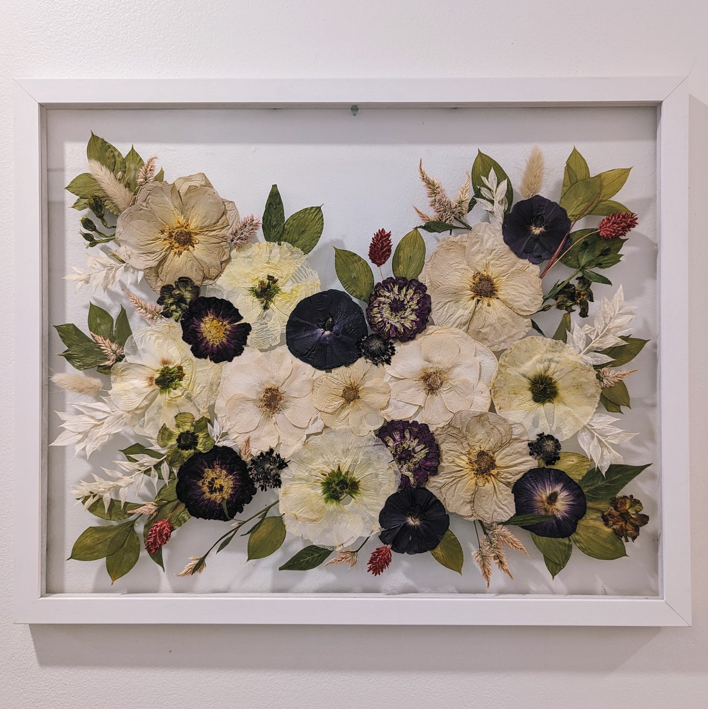 Unique art piece combining various pressed flowers and herbs in an abstract design.