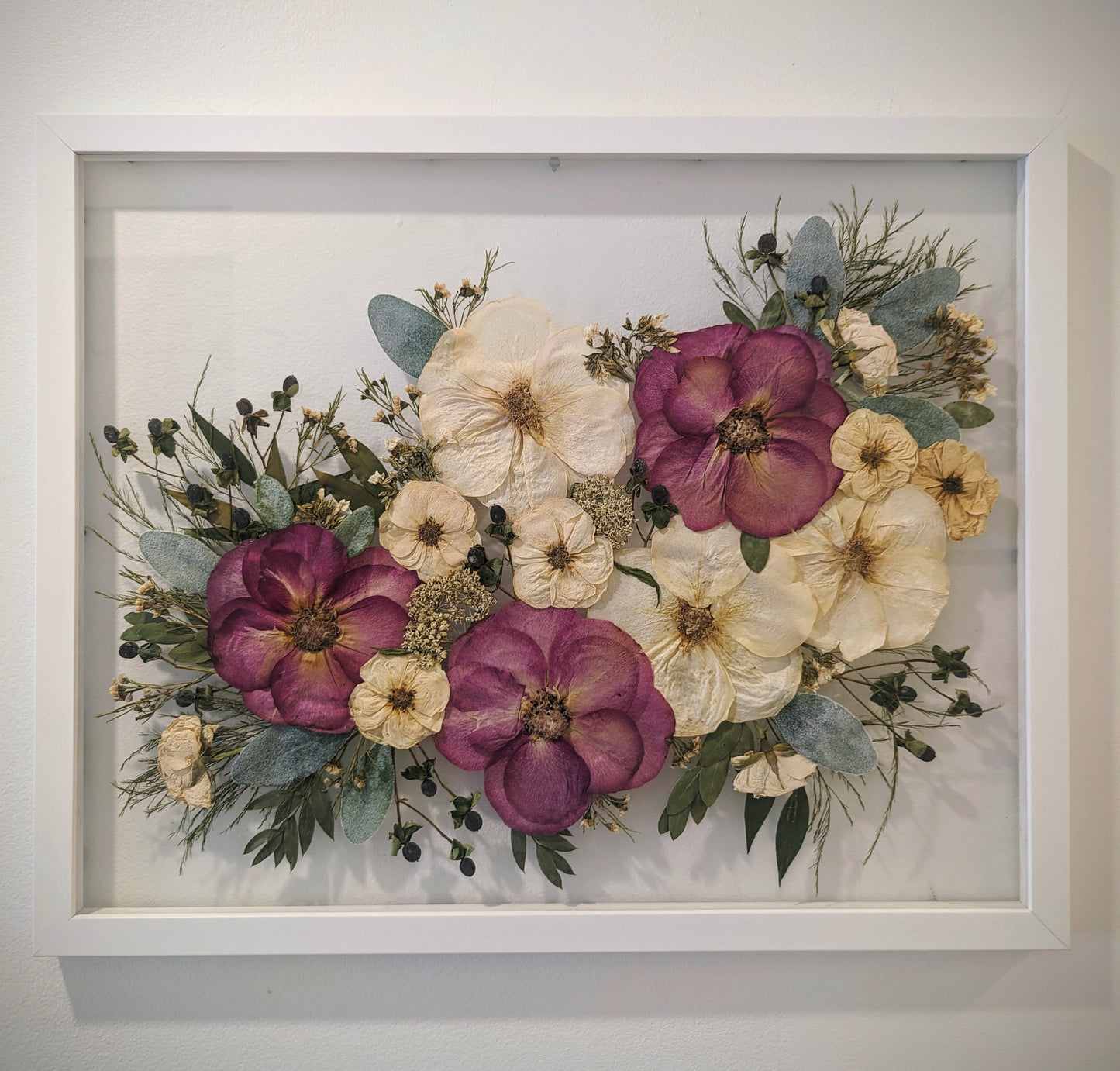 Unique art piece combining various pressed flowers and herbs in an abstract design.