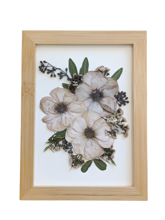Handmade pressed flower artwork with a vintage aesthetic in a gold frame.