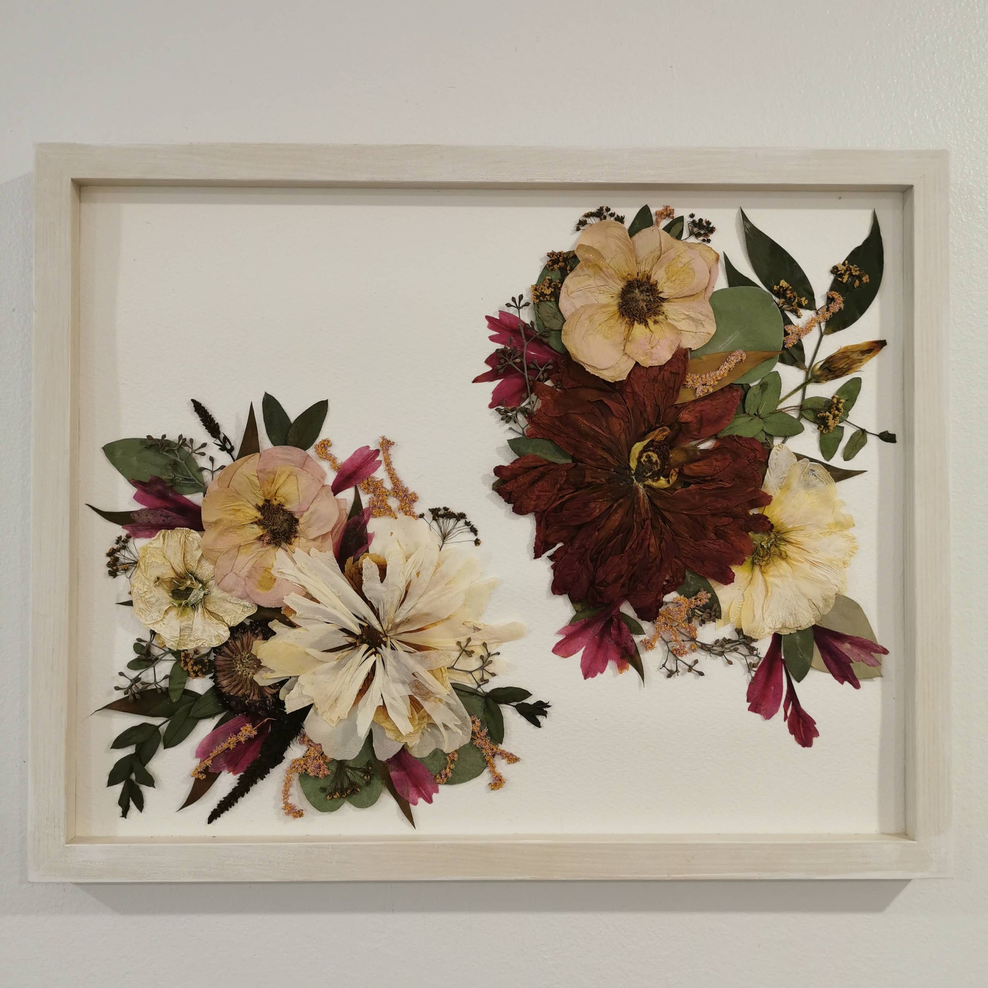 Pressed flower arrangement displayed as a centerpiece in a glass frame.