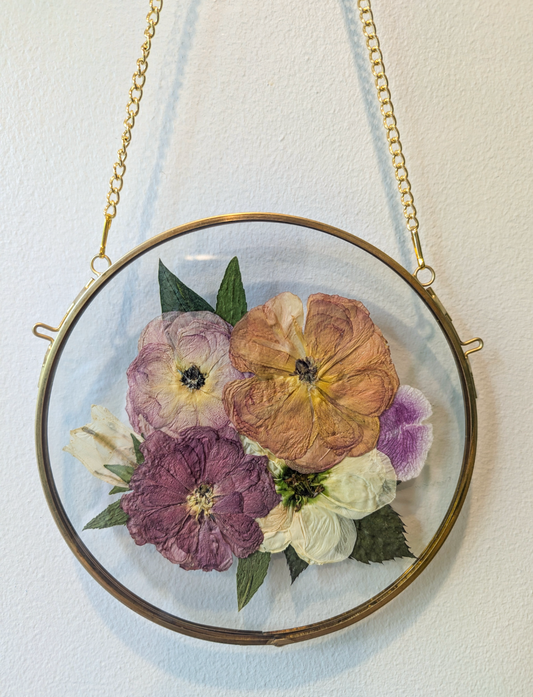Pressed flower arrangement displayed as a centerpiece in a glass frame.