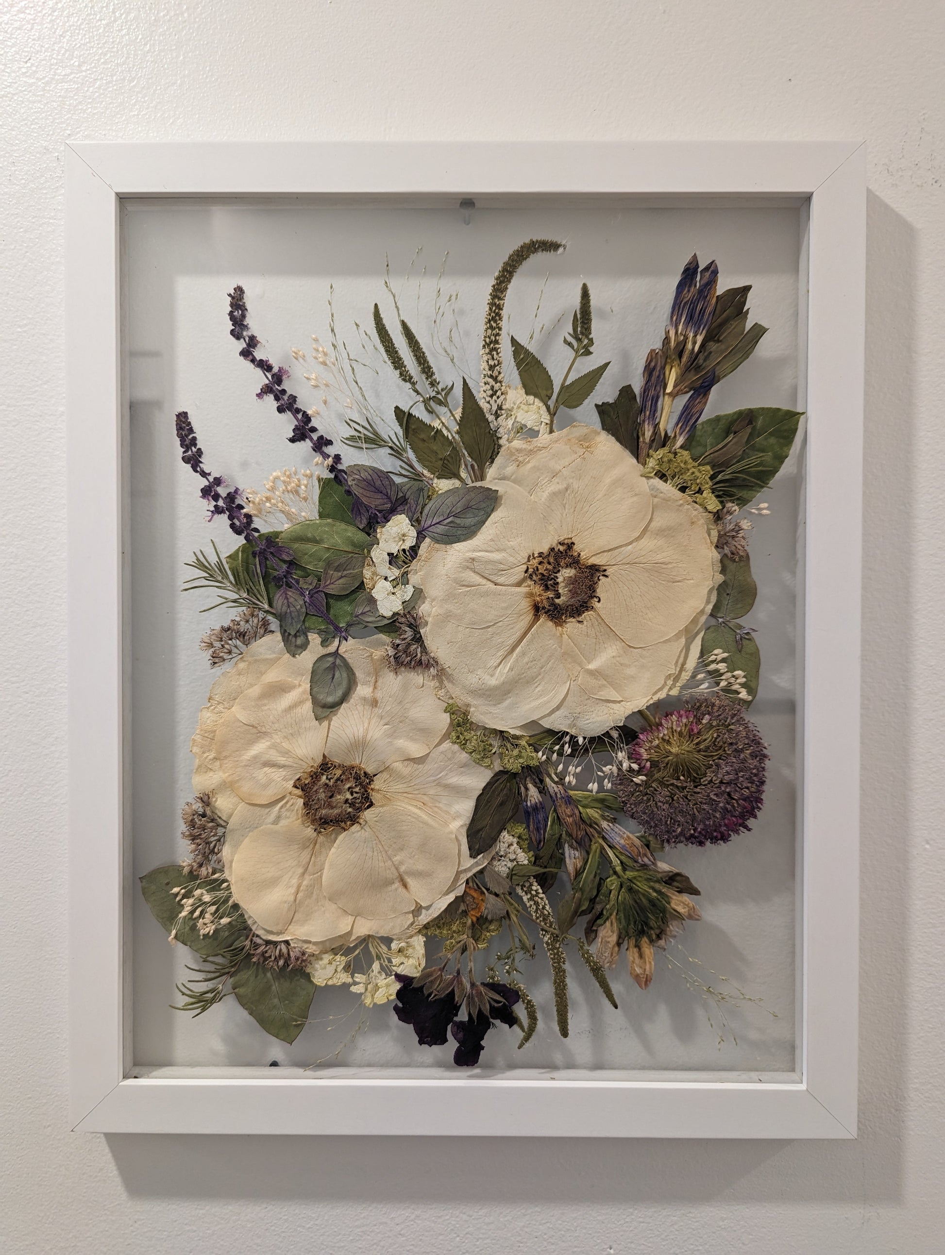 Pressed flower arrangement displayed as a centerpiece in a glass frame.